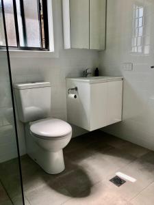 a white bathroom with a toilet and a sink at Lola’s@lennox in Lennox Head