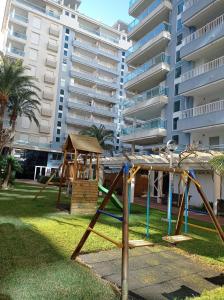 a playground in front of a large apartment building at Palmeras III Solo Familias Serviplaya!!! in Gandía