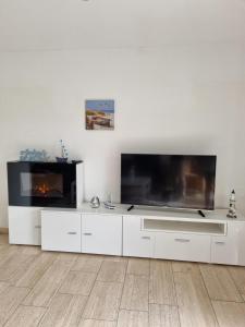 a living room with a large tv and white cabinets at Ferienhaus 1260 in Tossens in Butjadingen OT Tossens