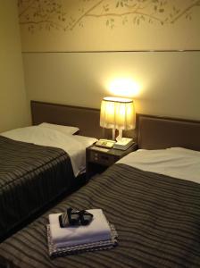 Dos camas en una habitación de hotel con un par de zapatos. en Hotel Heart Inn en Hakodate