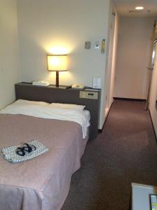 een hotelkamer met een bed met een lamp en schoenen erop bij Hotel Heart Inn in Hakodate +23 foto's
