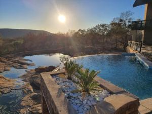 a swimming pool with a bridge over a river at Tholo Private Game Lodge in Warmbaths