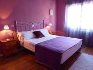 um quarto com uma cama com paredes roxas e uma janela em Casco Viejo Candeleda em Candeleda