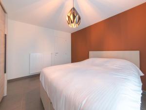 ein Schlafzimmer mit einem weißen Bett und einem Kronleuchter in der Unterkunft Apartment Ocean by Interhome in Bredene