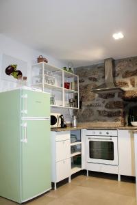 a kitchen with a green refrigerator and white cabinets at Batoca by Burra Velha - Private House in Celorico de Basto