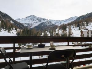a table with two coffee cups on a balcony with mountains at Studio Rosablanche D63 by Interhome in Siviez
