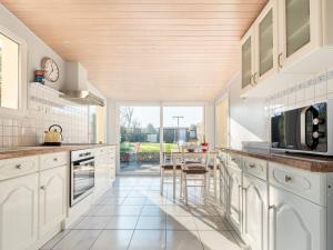 a kitchen with white cabinets and a large window at Holiday Home La petite maison by Interhome in Gouville-sur-Mer