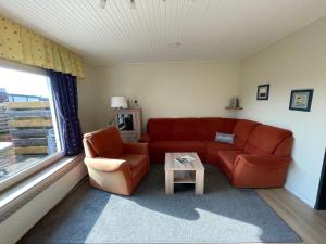 a living room with a red couch and a table at Holiday Home Kiel by Interhome in Norddeich