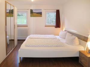 a white bed in a room with two windows at Holiday Home Hexenstüble by Interhome in Simonswald