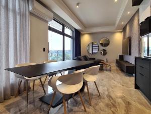 Luxurious Menlyn Maine 1 Bedroom on 12th Floor with Stunning Views & No Load Shedding في بريتوريا: غرفة طعام وغرفة معيشة مع طاولة وكراسي