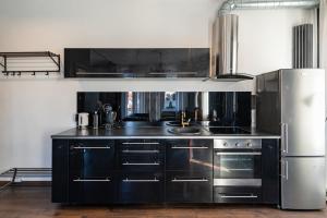 a kitchen with black cabinets and a stainless steel refrigerator at Retro Studio Old Town Apartment by Hostlovers in Kaunas