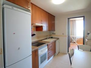 una cucina con armadi in legno e frigorifero bianco di Apartment Torre Mestral by Interhome a Cala de Finestrat