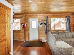ein Wohnzimmer mit einem Sofa und Holzwänden in der Unterkunft Holiday Home Alppikylä 4a paritalo by Interhome in Hyrynsalmi