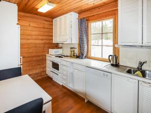 eine Küche mit weißen Geräten und einer Holzwand in der Unterkunft Holiday Home Alppikylä 4a paritalo by Interhome in Hyrynsalmi