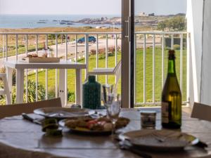 a table with a bottle of wine and a view of the ocean at Apartment Les Trois Iles-10 by Interhome in Quiberon +12 photos