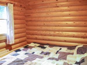 ein Schlafzimmer mit einem Bett in einer Holzwand in der Unterkunft Holiday Home Alppi 6a paritalo by Interhome in Hyrynsalmi