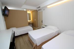 a hotel room with two beds and a tv at Hotel Don Zepe in Florianópolis