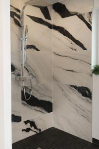 a bathroom with a shower with black and white wallpaper at Holiday Home Les Bruyères by Interhome in Tréflez