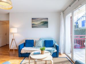 ein Wohnzimmer mit einem blauen Sofa und einem Tisch in der Unterkunft Apartment Les Jardins d'Oihana by Interhome in Bidart