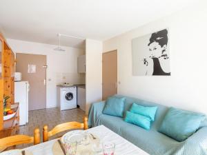 een woonkamer met een blauwe bank en een keuken bij Apartment Saint James-11 by Interhome in Le Lavandou