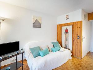 a living room with a white couch with blue pillows at Studio Les Pescadieres-1 by Interhome in Le Lavandou