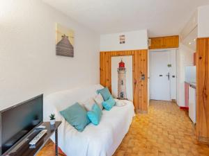 a living room with a white couch with blue pillows at Studio Les Pescadieres-1 by Interhome in Le Lavandou