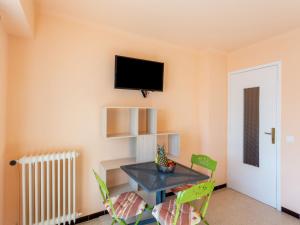 um quarto com uma mesa e cadeiras e uma televisão na parede em Studio Le Grand Large-2 by Interhome em Le Lavandou