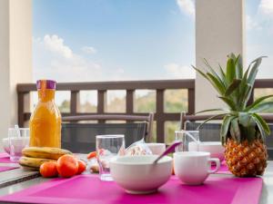 a pink table with food and a bottle of orange juice at Apartment L'Esquinade F6 225 by Interhome in Agay - Saint Raphael
