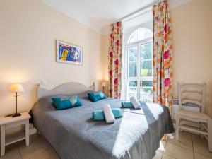 a bedroom with a bed with blue pillows and a window at Apartment Villa Francia-2 by Interhome in Cannes