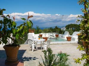 un patio con mesa, sillas y piscina en Apartment La Penultima-4 by Interhome en Ischia