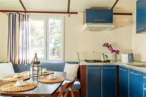 a kitchen with blue cabinets and a table with chairs at Comfort Lodge Maremma in Grosseto +12 photos
