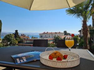 a table with a plate of food and a glass of orange juice at Downtown Apartment Ela in Opatija