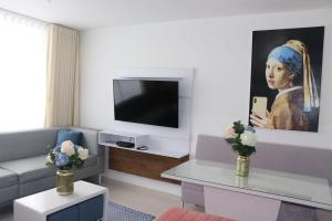 uma sala de estar com um sofá e uma pintura de uma mulher em Apartamento a 15 min de BUENAVISTA cerca a UNINORTE y CLINICA PORTOAZUL AA 2TV y parqueadero incluido em Barranquilla