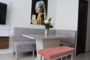 una mesa con un jarrón de flores y una pintura en Apartamento a 15 min de BUENAVISTA cerca a UNINORTE y CLINICA PORTOAZUL AA 2TV y parqueadero incluido en Barranquilla