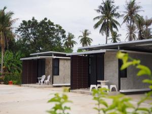 a house with a courtyard with chairs and palm trees at LOFT Zone by โรงแรมพรรณ in Ban Lahan Pa Phlu