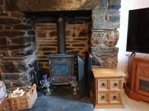 a stone fireplace with a stove in a room at 1 Park Terrace in Corris