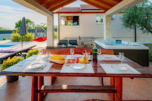a table with food and wine glasses on a patio at Villa Lorema-pet friendly on 5000 sqm garden,pool, jacuzzi, billiard&PS5 in Sveti Filip i Jakov