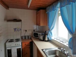 a kitchen with a stove and a sink and a window at 1 Park Terrace in Corris