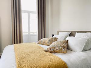 a bed with white sheets and pillows and a window at La Cour Tellier in Rilly-la-Montagne