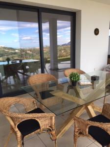 szklanym stołem i krzesłami w pokoju z widokiem w obiekcie Stunning Apartment close to golf Mijas Spain w mieście Mijas