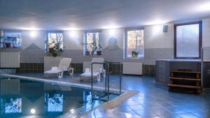 una piscina con sillas, una mesa y agua en Rókabérc Vadászház Hotel, en Erdőbénye