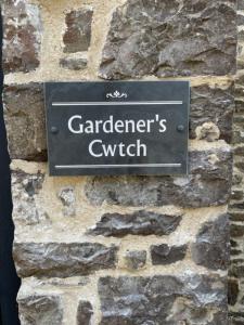 a sign on the side of a stone wall at Gardener's Cwtch, Llwynhelig Manor in Llandeilo