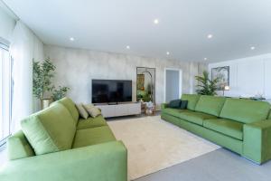 een woonkamer met twee groene banken en een flatscreen-tv bij T3 Pelican Bay in Nazaré