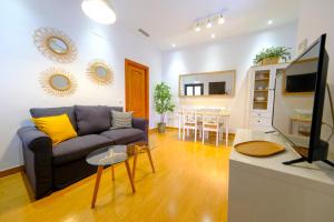 uma sala de estar com um sofá e uma televisão em Patio Rialto Apartment em Sevilha