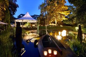 a small boat with candles in a pond at night at Parkhotel Gütersloh in Gütersloh