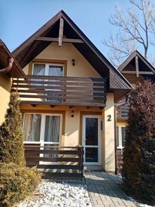 a small yellow house with a porch and a door at Chatka Tatry in Veľký Slavkov