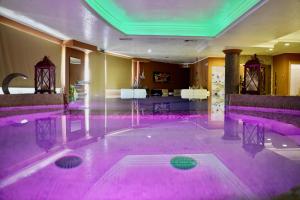 Hotel Roscianum Welness SPA في روسانو: حمام سباحة مع إضاءة وردية في الغرفة