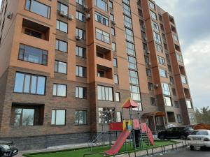 une aire de jeux en face d'un grand bâtiment dans l'établissement Двухкомнатная квартира на самом берегу реки, à Pavlodar