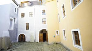 an alleyway between two white buildings with brown doors at FeWo Zeitreise I - zauberhafte Altstadtmomente erleben in Görlitz