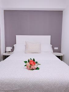 a white bed with a bouquet of flowers on it at Hostal El Castillo Alcala De Guadaira in Alcalá de Guadaira